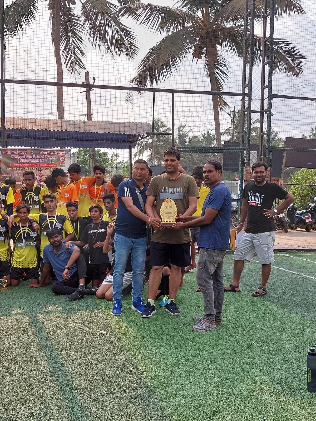 Officials hold an award plaque on the pitch