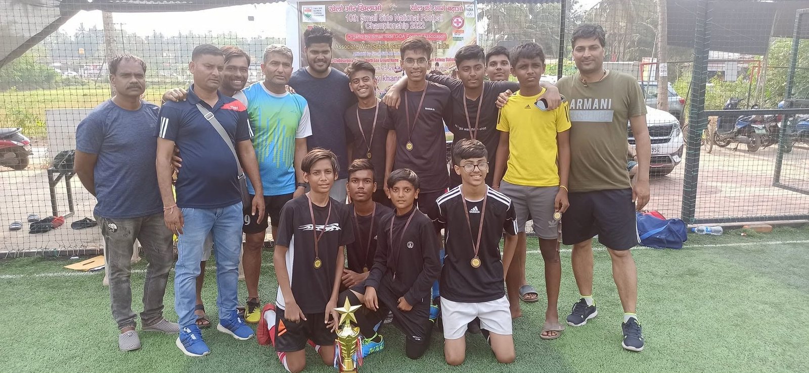 Team in black kits with coaches on a turf ground