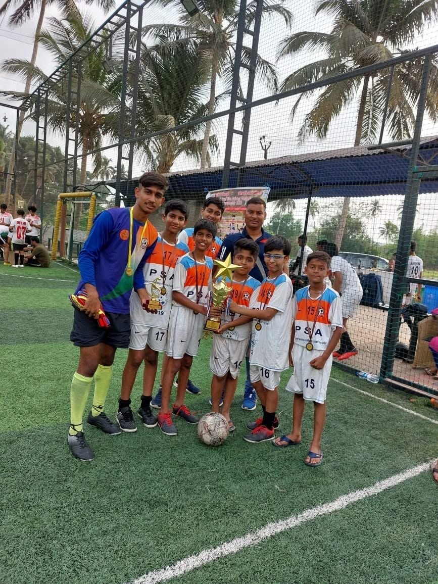 Young players hold a trophy on a turf pitch